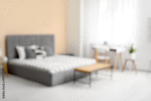 Stylish bedroom with bed, bedside table and workplace, blurred view © Pixel-Shot