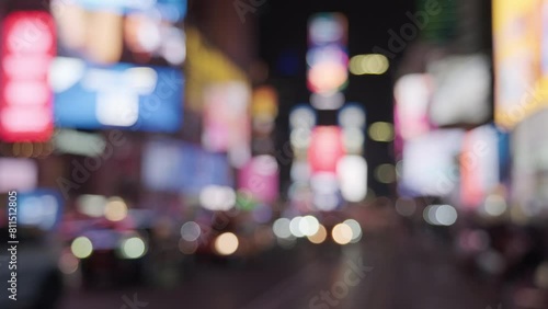 Blurred bokeh view of Times Square at night with billboards lit up and cars driving through