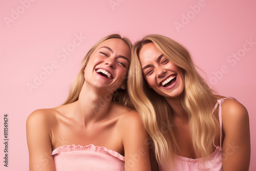 studio portrait of two laughing woman friends on colour background
