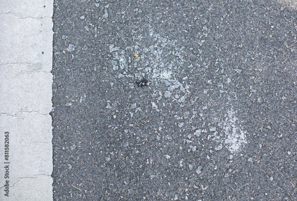 Shards of glass or broken glass lie on the asphalt road.