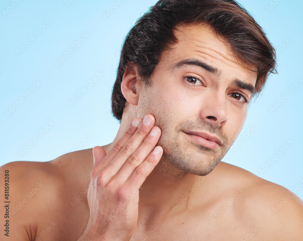 Obraz premium Man, portrait and studio for beauty or skincare with facial daily, dermatology and morning routine for wellness or self care. Person, blue background and serious for grooming with cosmetics and fresh