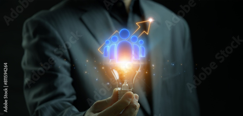 Business teamwork, team building, work group and human resources concept. Businessman showing glowing lightbulb with neon line group of businessman with up arrow behind.