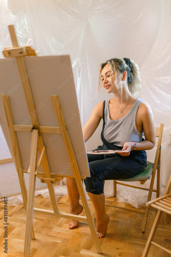 Satisfied female artist posing near new picture next to easel Satisfied female artist posing near new picture next to easel