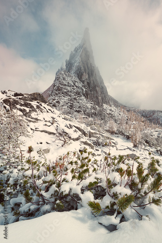 The jagged spire of Prusik Peak peeks through the clouds in the photo