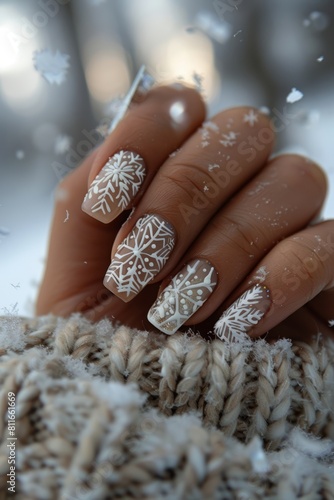 A woman holding her nails with snowflakes on them.