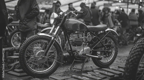A black and white photo of a motorcycle with a group of people in the background