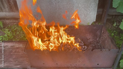 the fire is burning in an iron grill, the fire is burning in the coals against the background of green grass