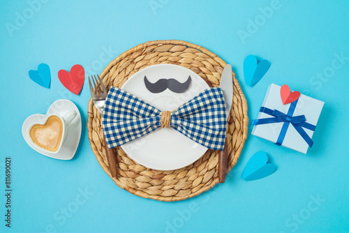 Table setting for Father's day breakfast with heart shape coffee cup, plate and gift box on blue background. Top view, flat lay