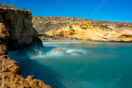 Beautiful cove in the Cabo Cope and Puntas de Calnegre Regional Park, with crystal clear waters and yellow rock cliffs with long exposure photo