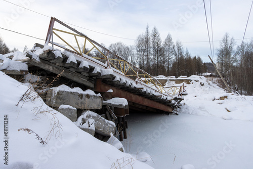 View of the collapsed road bridge. Collapsed bridge over a small river. Fallen damaged bridge. Consequences of an emergency. Cold winter weather. A lot of snow. photo