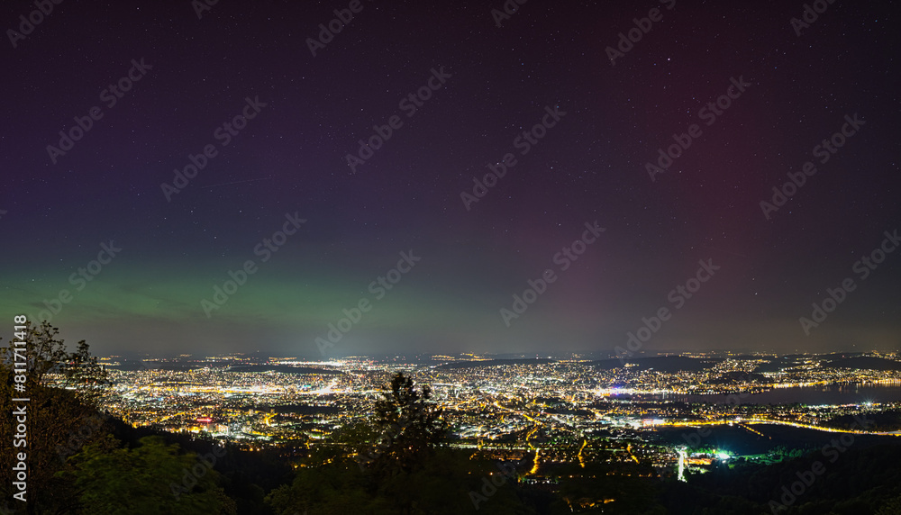 Fototapeta premium Large panorama of the city of Zurich in Switzerland from Uetliberg at night with northern lights