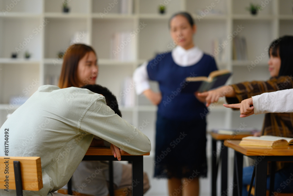 Student man sleeping at desk in classroom during lecture Student man sleeping at desk in classroom during lecture