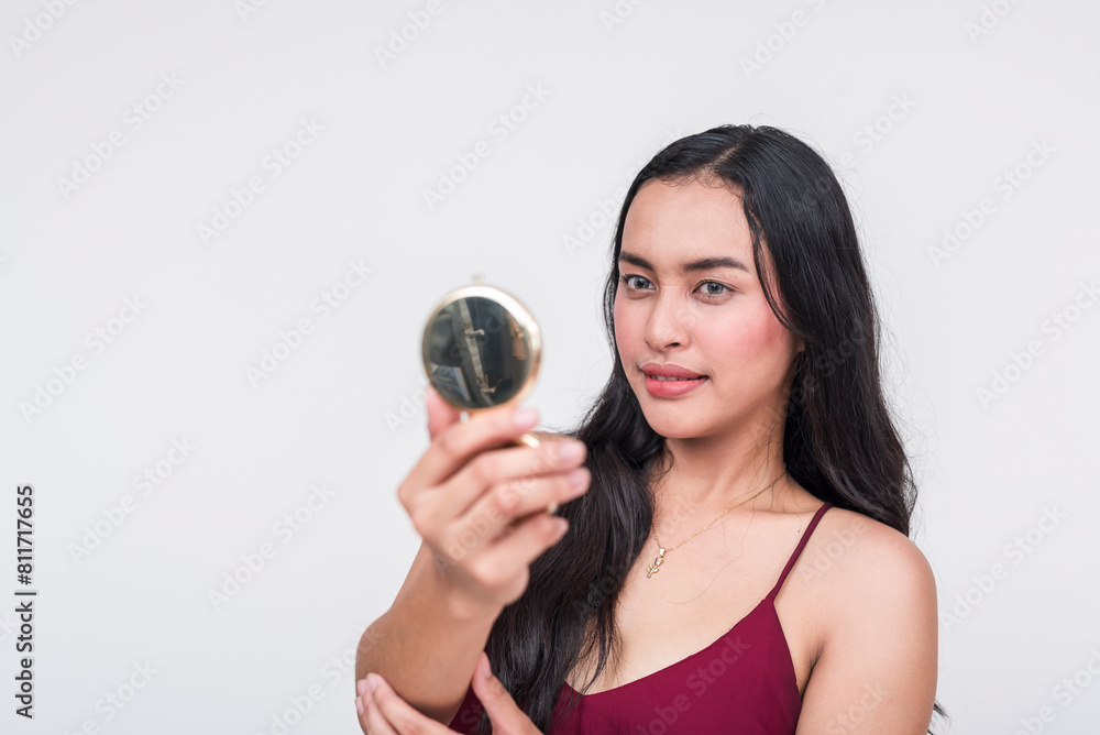 A beautiful young Asian lady checking her appearance with her pocket mirror before a date. Isolated on a white background. A beautiful young Asian lady checking her appearance with her pocket mirror before a date. Isolated on a white background.