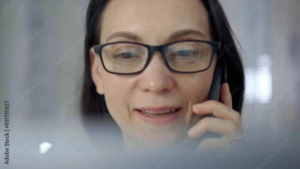 Cheerful smiling woman with glasses using a mobile phone, blurred background. Lifestyle and business concepts Cheerful smiling woman with glasses using a mobile phone, blurred background. Lifestyle and business concepts