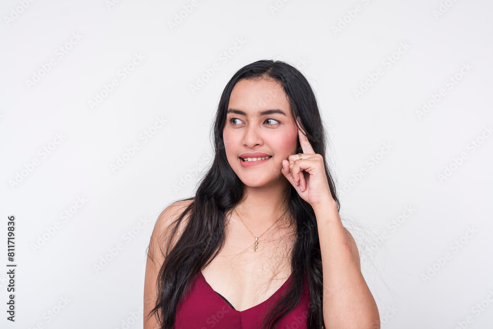 Fototapeta premium A young Asian lady in a chic maroon dress thinking of naughty and mischievous thoughts while biting her lip.