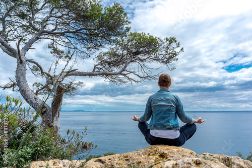 Wallpaper Mural Junge Frau meditiert an einem Felsvorsprung am Meer mit Baum Torontodigital.ca