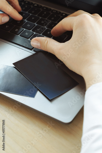 person typing on a laptop. Business card near the notebook