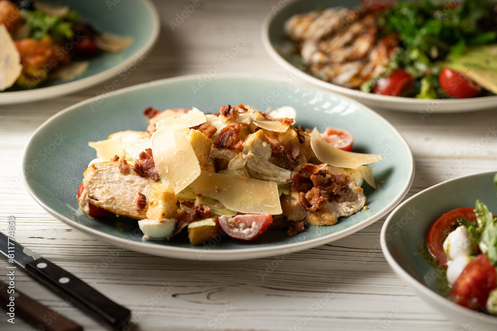 Caesar salad with chicken breast, tomatoes and sliced parmesan cheese. Meals are served on the table in the restaurant. Restaurant menu Caesar salad with chicken breast, tomatoes and sliced parmesan cheese. Meals are served on the table in the restaurant. Restaurant menu
