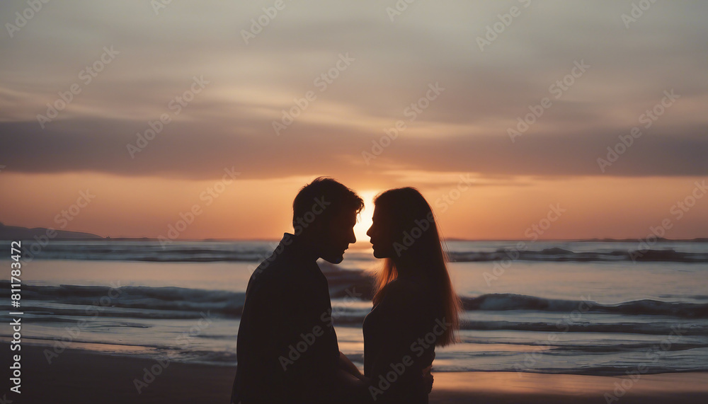 silhouette of lovers hugging each other and watching the sunset on the beach
