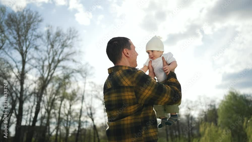 Father throws child up park. Family having fun outside in nature. Joyful moment between father and child. Happy baby smiles while playing. Family bonding in sunny park. Father love for child outdoors. Father throws child up park. Family having fun outside in nature. Joyful moment between father and child. Happy baby smiles while playing. Family bonding in sunny park. Father love for child outdoors.