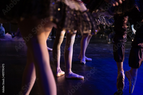 Legs of ballerinas standing backstage during a ballet performance.