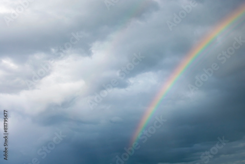 Summer rainbow colors against dark clouds. © Anatoliy