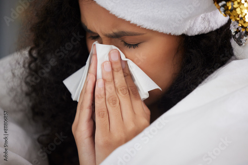 Woman, blanket and sick with tissue on Christmas or blowing nose in home, holiday or symptoms. Female person, hat and flu allergies or virus for festive season with cold weather, fever or vacation photo