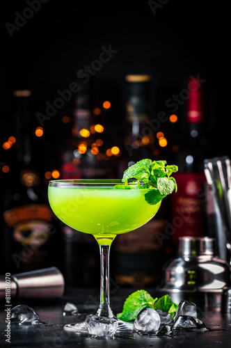 Summer green cocktail drink with gin, liqueur, lime, juice, mint and ice. Black bar counter background, steel bar tools and bottles © 5ph