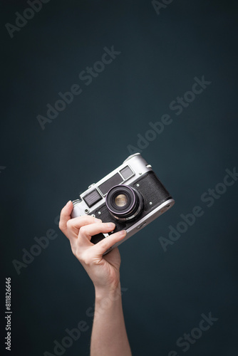 retro camera in a woman's hand on a dark background.