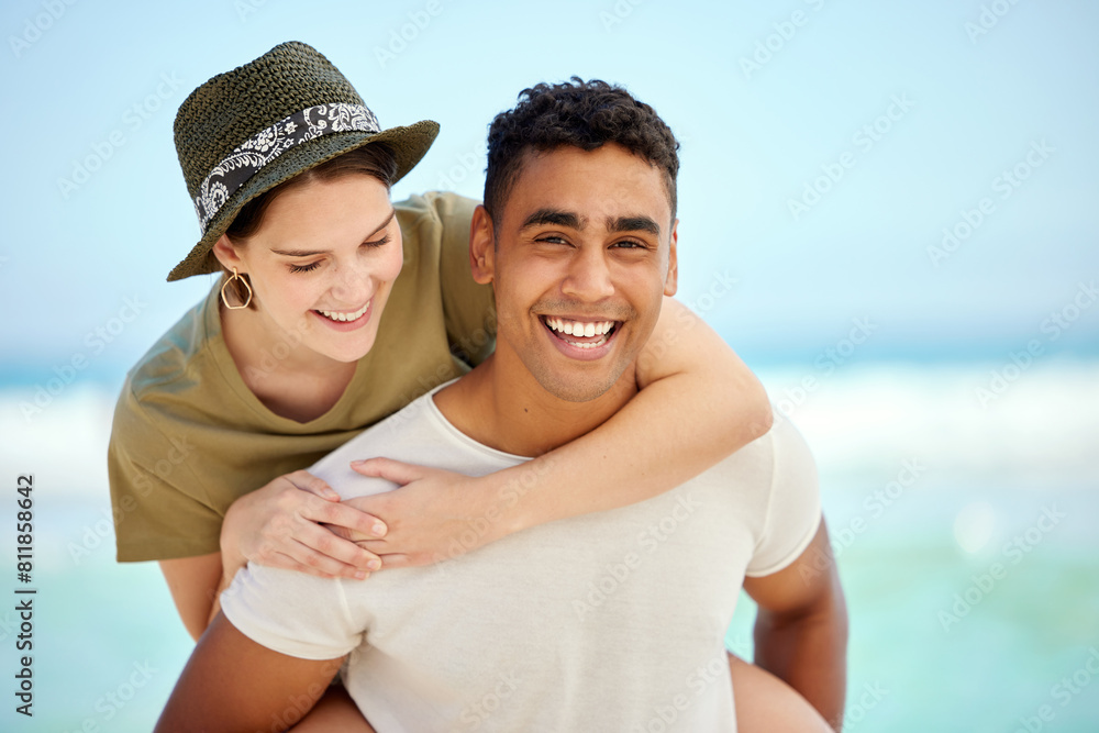 Obraz premium Portrait, smile and couple piggyback at beach on holiday, travel or summer vacation together. Face, interracial man and woman at sea for adventure date, laughing and hug for support by ocean water
