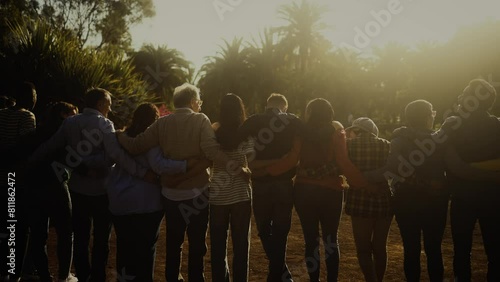 Back view of happy multigenerational people having fun in a public park during sunset time
