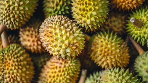 fresh durian fruits  including yellow and green varieties  are displayed for sale in a market alongside a yellow flower