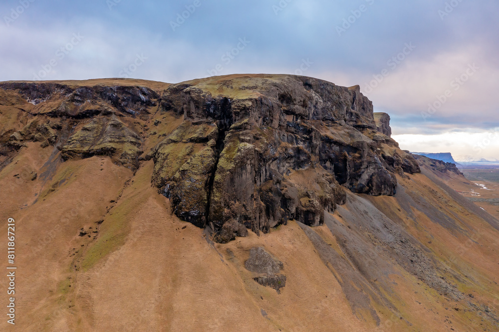 Obraz premium Aerial view high mountain in east of Iceland. High rocks covered with moss. Blue gray cloudy sky.