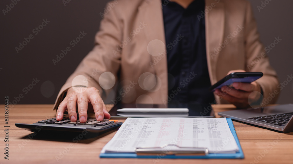A man is sitting at a desk with a calculator, a cell phone, and a laptop, Homework A man is sitting at a desk with a calculator, a cell phone, and a laptop, Homework
