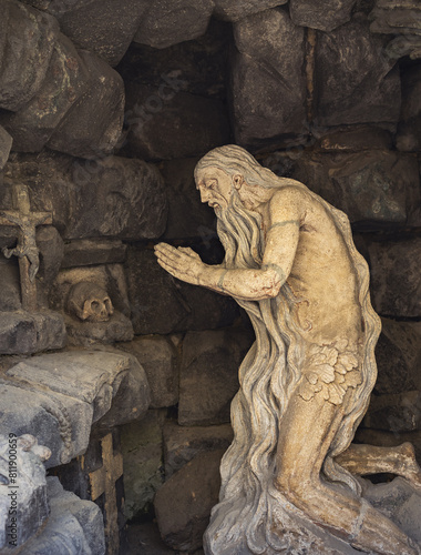 An old hermit prays in a cave. A stone statue of a hermit monk near St. George's Cathedral , Lviv, Ukraine