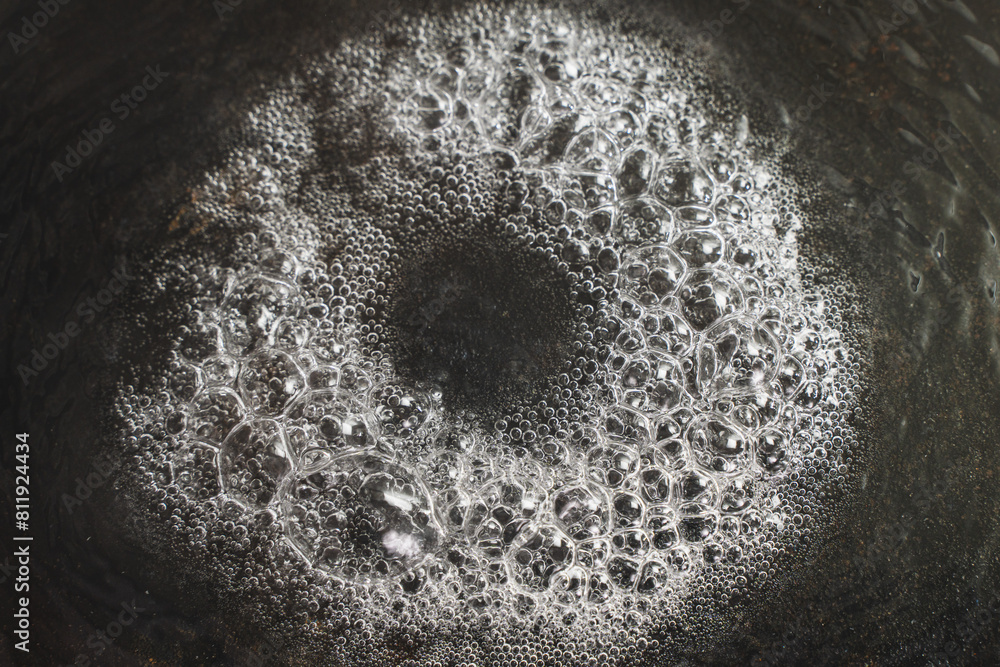 Boiling little on a black background. Close-up of melted butter in a cast-iron skillet. Selected focus. Boiling little on a black background. Close-up of melted butter in a cast-iron skillet. Selected focus.