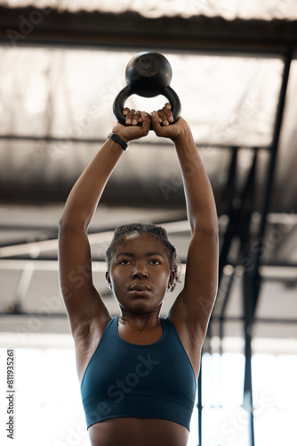 Black woman, fitness and workout with kettlebell in gym for muscle, wellness or body health challenge. Sport, strong bodybuilder and weightlifting for exercise, training and power for energy in club