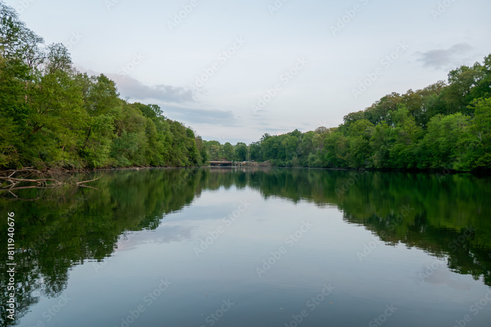 a lake surrounded by lush trees and some sky in the background