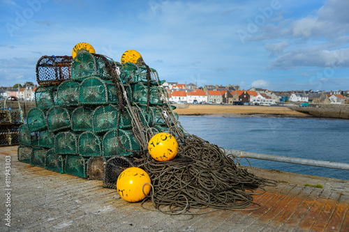 Lobster and crab baskets with yellow buoys on a jetty at Anstruther (Ainster or Enster) in Fife, on the east coast of Scotland. Horizontal landscape format with copy space.