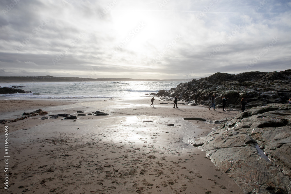 People and dogs backlit on Godrevy Beach in the UK.