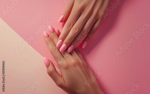 Woman's hands with pastel pink nails on a dual-tone background.