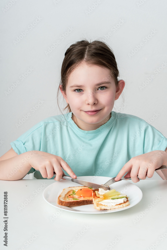 Cute little girl eating fried egg with toast and vegetables. The concept is delicious and proper food. selected focus. Cute little girl eating fried egg with toast and vegetables. The concept is delicious and proper food. selected focus.