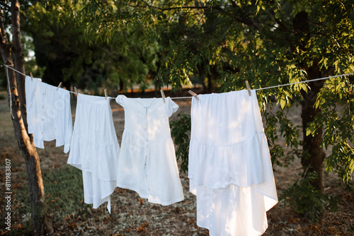 White dresses hanging on rope with pins outdoor close up.