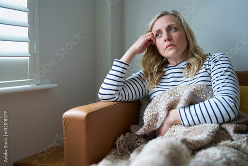 Mature Economically Inactive Woman Suffering With Long Term Illness Sitting On Sofa At Home