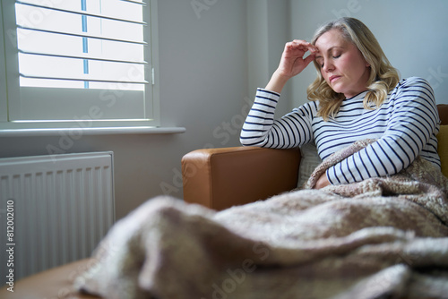 Mature Economically Inactive Woman Suffering With Long Term Illness Sitting On Sofa At Home