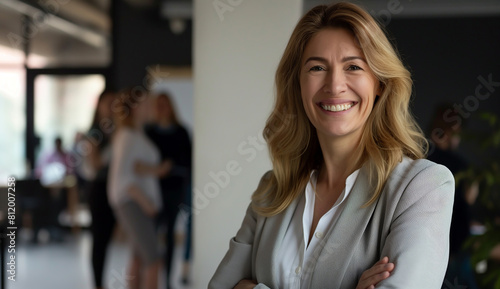 A smiling businesswoman standing in front of a team members in an office background with copy space for text