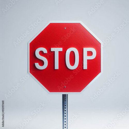 A stop sign is shown in red with a white border. The sign is octagonal and features the word \"STOP\" in white letters. The background is a light gray.