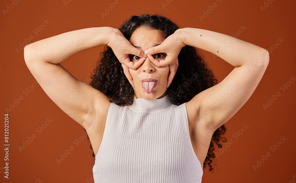 Goofy, tongue and girl in studio, portrait and funny face of Gen z, relax and humor with circle on eyes. Brown background, comedy and comic person with mouth, fashion and emoji in mockup and playful