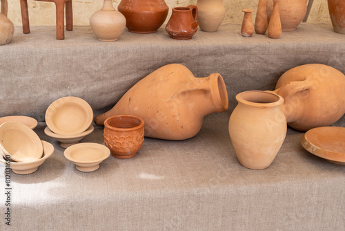 A table with many different types of pottery, including bowls, vases, and cups. The table is covered in a cloth and the pottery is arranged in a way that makes it easy to see photo