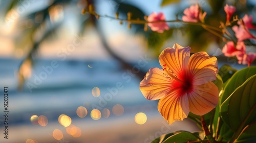 Close-up of a vibrant beach flower in full bloom  with blurred palm trees and a sparkling ocean in the background